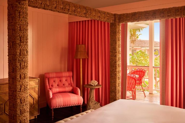 Habitación coral con sillón tapizado y terraza con vistas tropicales en Coral Sands Inn & Cottages