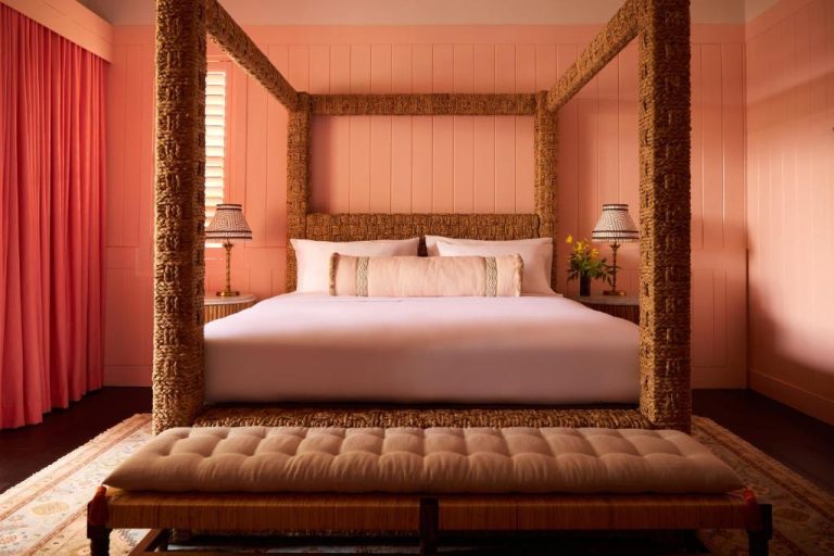 Habitación con cama de dosel de fibra natural y paredes rosas en Coral Sands Inn & Cottages