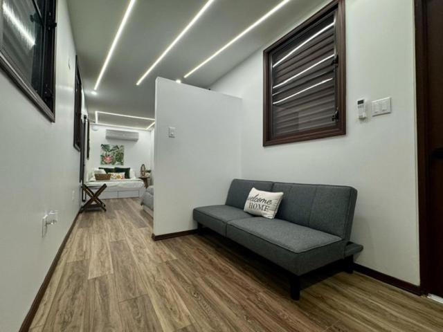Sala de estar con sofá gris y suelo de madera en Hacienda del Sur con iluminación LED moderna