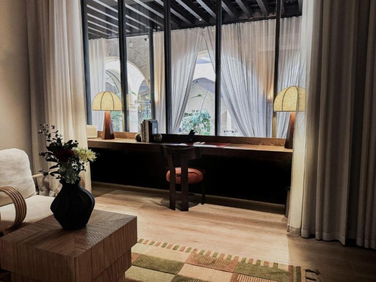 Escritorio de madera con lámparas y silla frente a ventanal en Nobis Hotel Palma Design Hotels