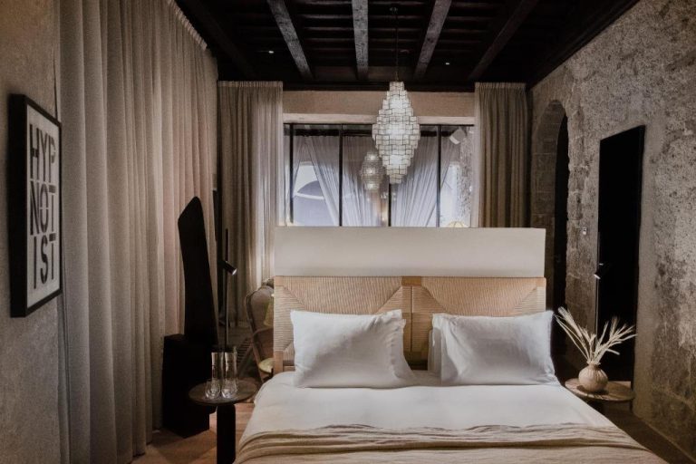 Habitación doble con decoración rústica y elegante en Nobis Hotel Palma, con paredes de piedra y lámpara de araña