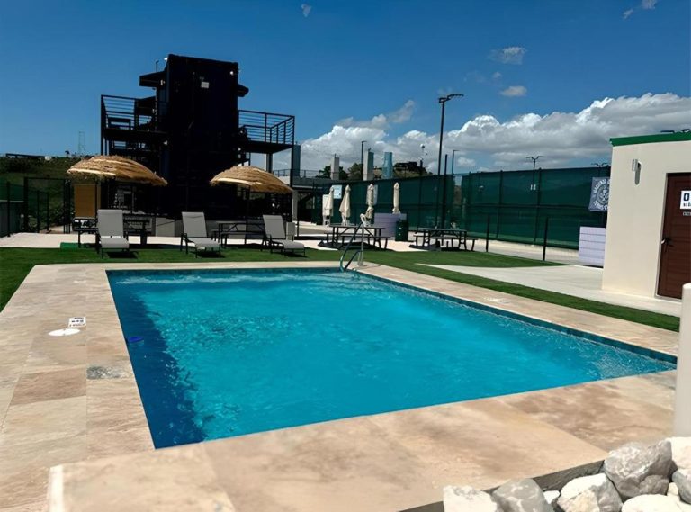 Piscina exterior con tumbonas y sombrillas de palma en Hacienda del Sur bajo cielo azul