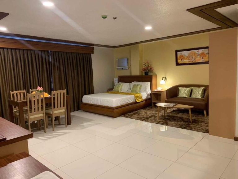 Suite espaciosa con cama doble, zona de estar y comedor en Surigao Royal Regency Suites