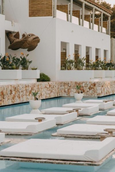 Piscina con hamacas flotantes blancas y escultura de pez en Lago Resort Menorca Suites del Lago Adults Only