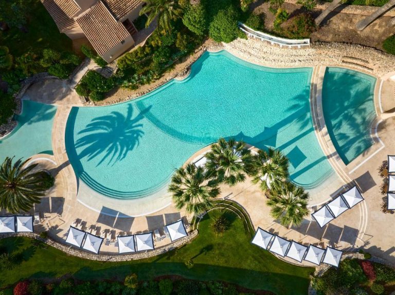Vista aérea de la piscina exterior del Vilalara Grand Hotel Algarve rodeada de palmeras y tumbonas