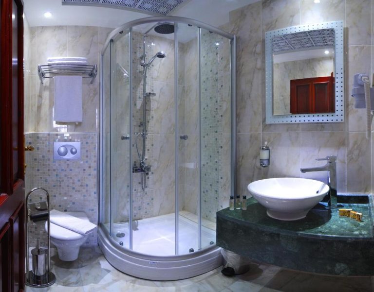 Baño de lujo con ducha circular y lavabo sobre encimera de mármol verde en White Garden Hotel Adult Only