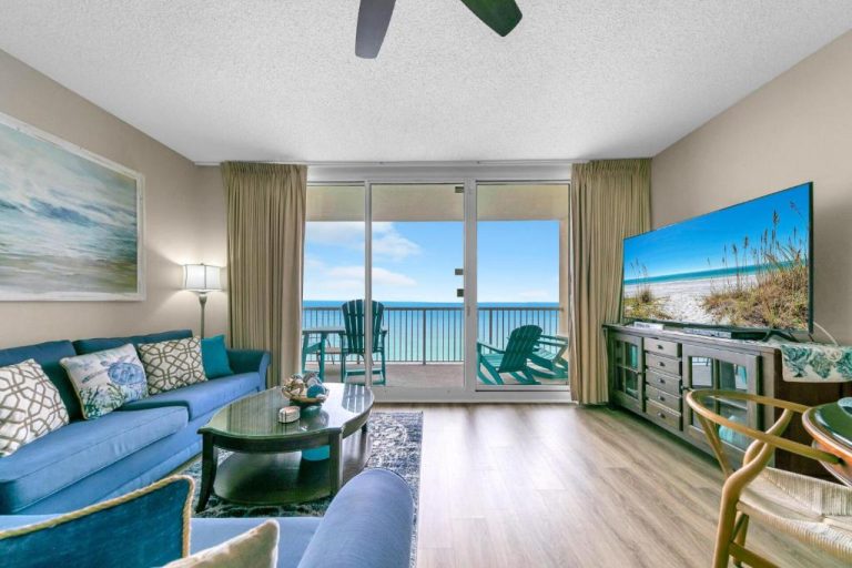 Salón con sofás azules y vistas directas al mar desde balcón en apartamento Panama City Beach Florida