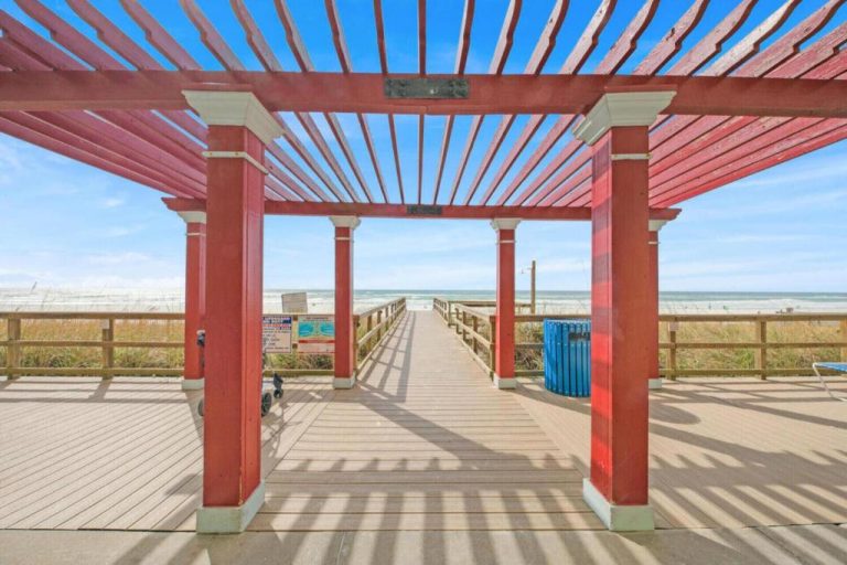 Pasarela de madera con pérgola roja que da acceso directo a la playa en Panama City Beach, Florida