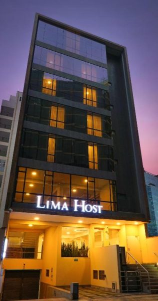 Fachada exterior iluminada del Hotel Lima Host en Lima, edificio moderno de cristal y varios pisos