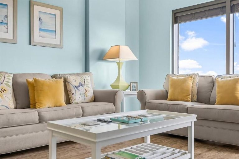 Sala de estar luminosa con sofás beige y cojines dorados en Origin 1227 Beachy Dreams