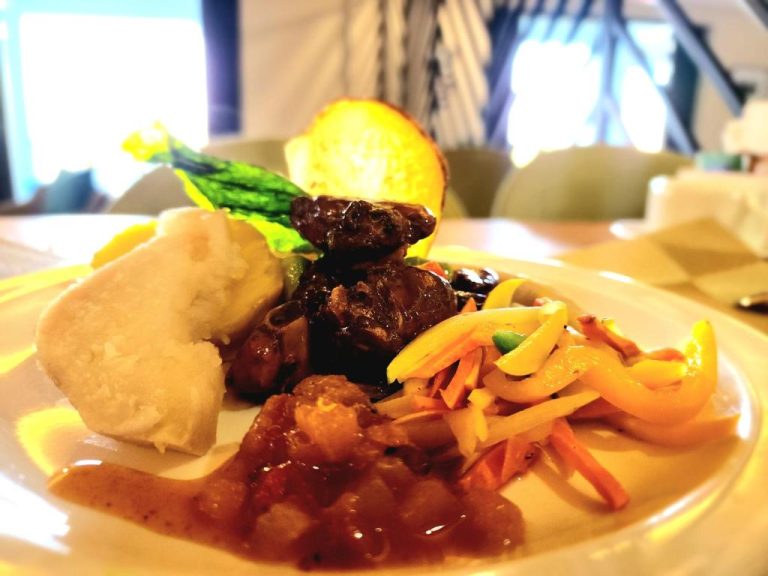 Plato típico jamaicano con carne estofada, verduras salteadas y pan en el Hotel 39 Jamaica