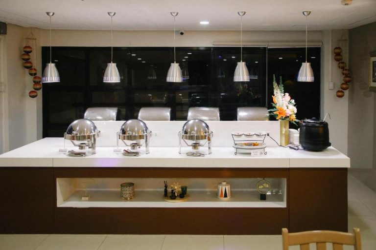 Zona de buffet con chafing dishes en el Surigao Royal Regency Suites, restaurante con iluminación elegante