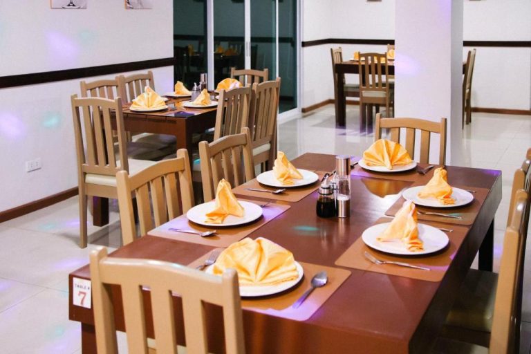 Comedor elegante con mesas bien puestas y servilletas naranjas en Surigao Royal Regency Suites