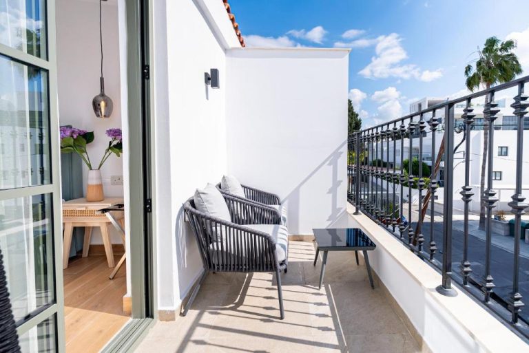 Terraza exterior con sillas y mesa del Loft Centrale, con vistas al entorno urbano y cielo azul