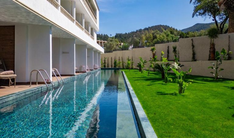 Piscina lap pool exterior con jardín tropical del Samara Hotel Bodrum Ultra All Inclusive con vistas a la montaña