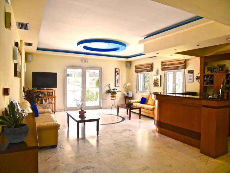 Recepción y zona de lobby luminosa de Kanakis Blue Beach Apartments con sofás y mostrador de recepción