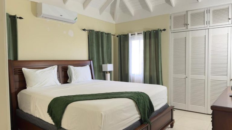 Habitación doble con cama king size y cortinas verdes en Jamnick Vacation Rentals, Jamaica