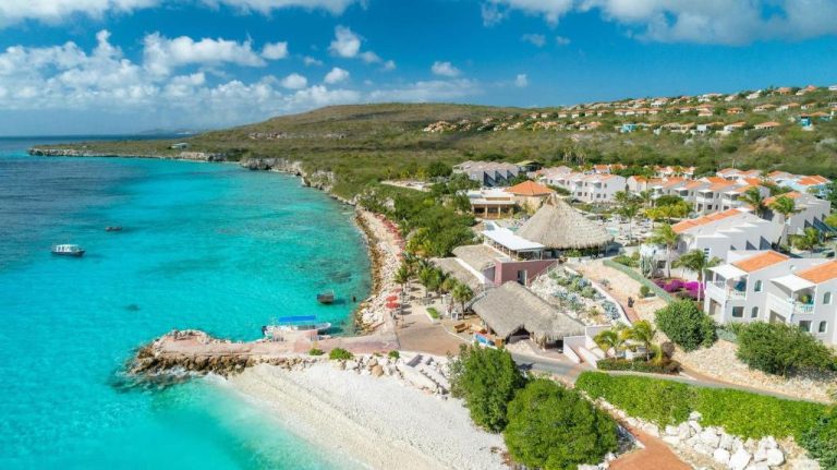 Vista aérea del Coral Estate Luxury Resort con aguas turquesas, villas blancas y acceso privado a la playa