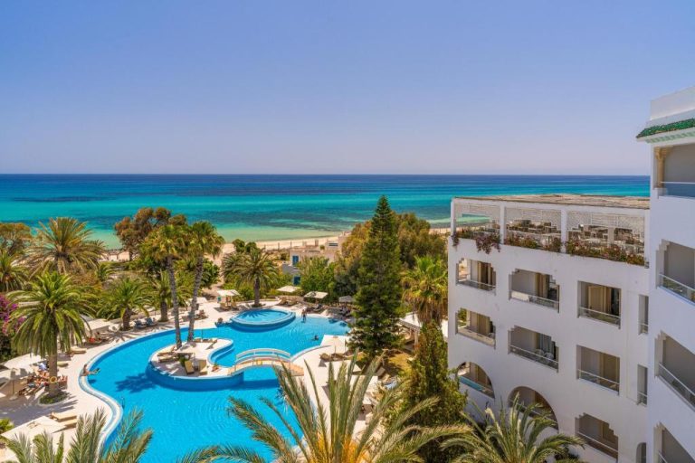 Piscina exterior con palmeras y vista al mar turquesa del Hotel Sol Azur en Túnez