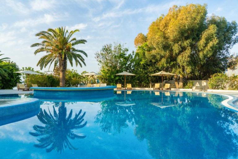Piscina exterior de aguas cristalinas con hamacas y palmeras tropicales en el Hotel Sol Azur
