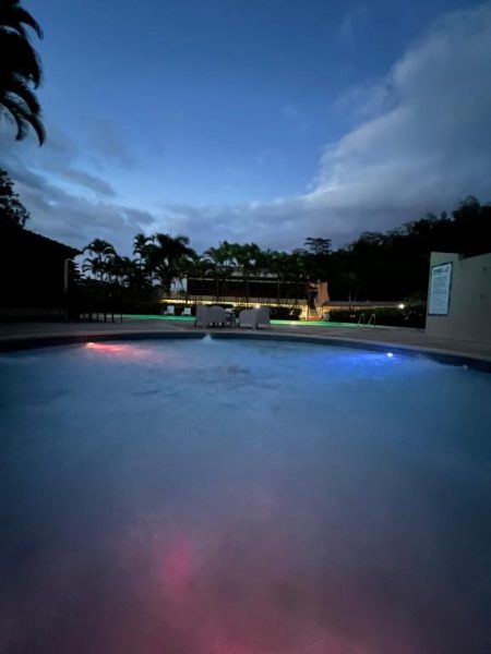 Piscina iluminada de noche con luces de colores en Hacienda Villa Sotomayor rodeada de palmeras