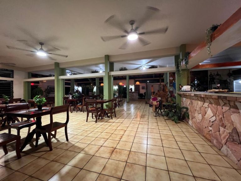 Restaurante interior de Hacienda Villa Sotomayor con mesas de madera, ventiladores de techo y barra de piedra