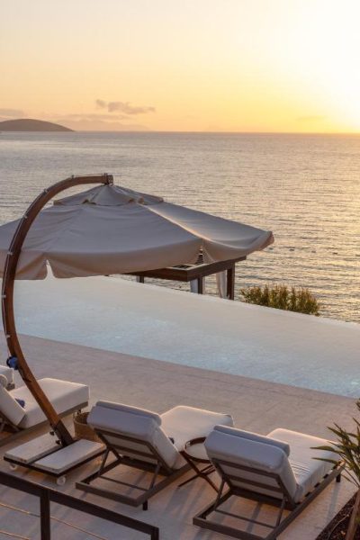 Piscina infinita con vistas al mar y tumbonas al atardecer en Allium Bodrum Resort & Spa