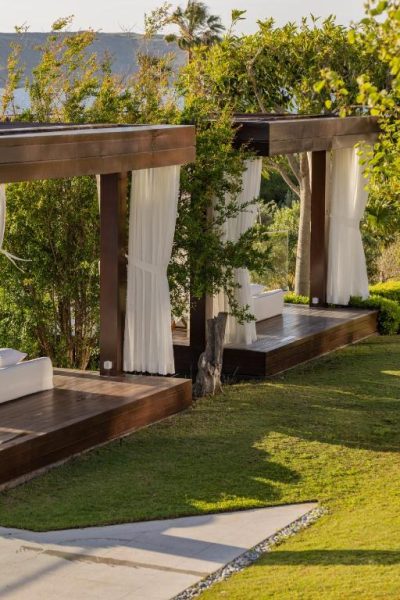 Cabañas de madera con cortinas blancas y jardines tropicales en Allium Bodrum Resort & Spa