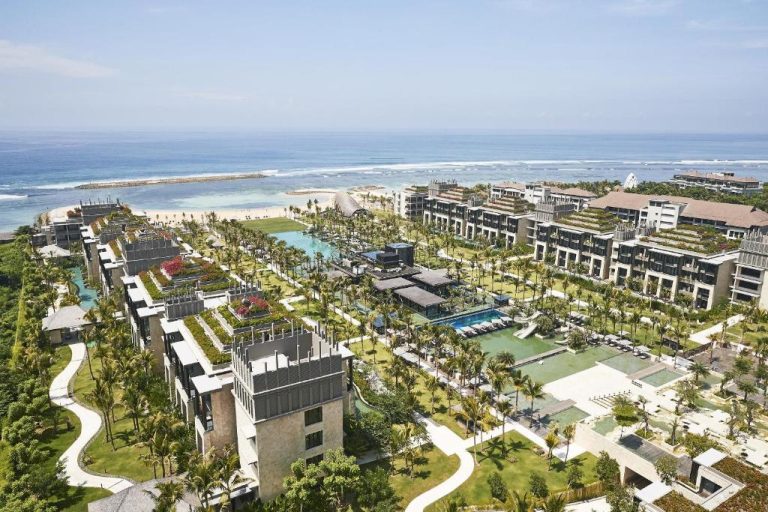 Vista aérea del resort The Apurva Kempinski Bali con piscinas, jardines tropicales y playa al fondo