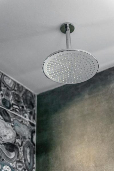Ducha de lluvia empotrada en el techo con azulejos de mármol en el spa del Pasham Residence