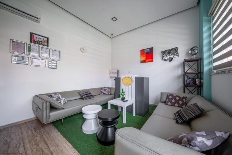 Sala de estar con sofás grises y área de recepción en Pasham Residence con decoración moderna