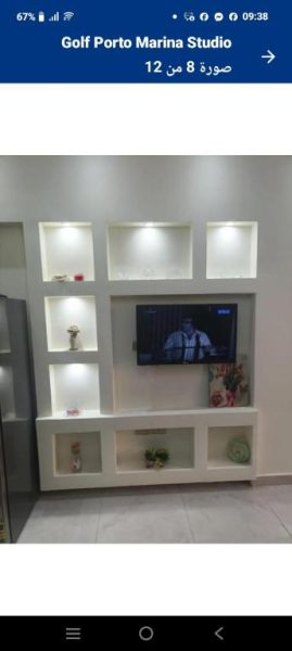 Salón moderno con televisor y estanterías iluminadas en el estudio Porto Golf Marina