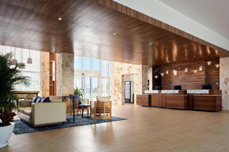Lobby y recepción moderna del Fairfield Inn & Suites by Marriott Cancun Airport con decoración en madera
