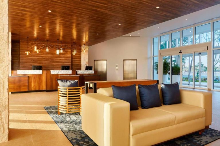 Lobby y recepción del Fairfield Inn & Suites by Marriott Cancun Airport con sofás y techo de madera