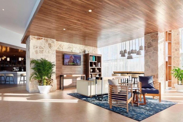 Lobby lounge con sillones y bar del Fairfield Inn & Suites by Marriott Cancun Airport