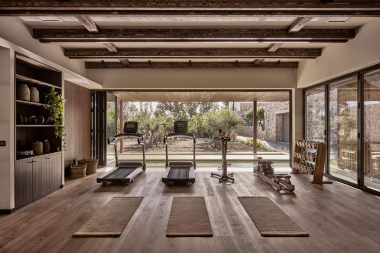 Gimnasio moderno con cintas de correr y vistas al jardín en Theros All Suite Hotel Adults Only