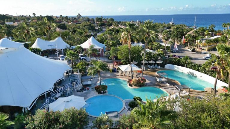 Vista aérea de las piscinas exteriores y jardines tropicales del Chogogo Dive & Beach Resort Curaçao