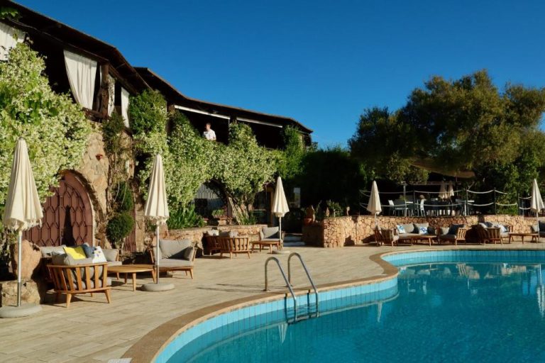 Piscina exterior con tumbonas y sombrillas junto a la fachada de piedra del Hotel Don Diego