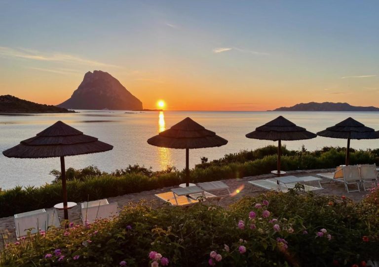 Puesta de sol sobre el mar con sombrillas y tumbonas en el Hotel Don Diego Cerdeña