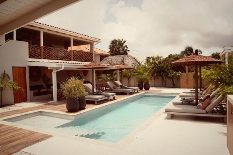 Piscina exterior con tumbonas y sombrillas del Yucca Mini Boutique Hotel Adults Only en Curazao