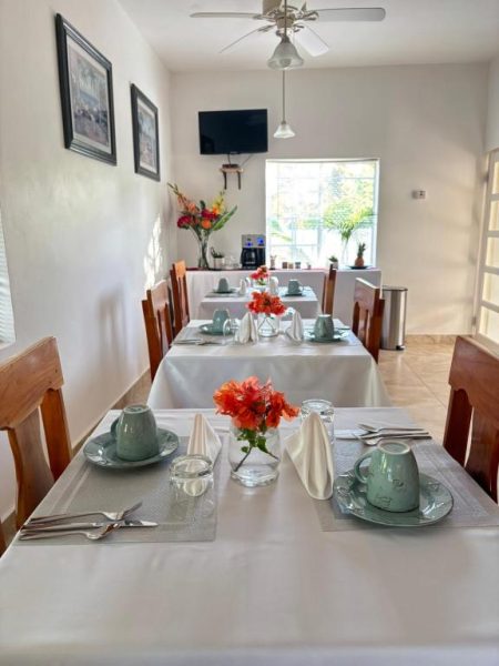 Comedor elegante con mesas blancas y flores rojas para el desayuno en Sommerville Resorts