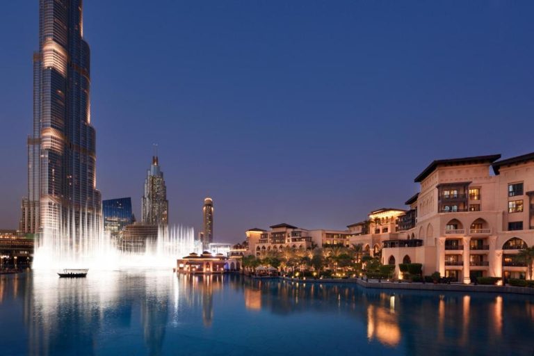 Vista nocturna del Palace Downtown Dubai con la fuente del Burj Khalifa iluminada frente al hotel