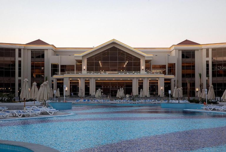 Amplia piscina exterior con tumbonas y sombrillas del hotel SRNTY Sahl Hasheesh al atardecer