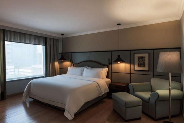 Habitación king size con sillón y ventanal panorámico en el Hotel Poblado Plaza