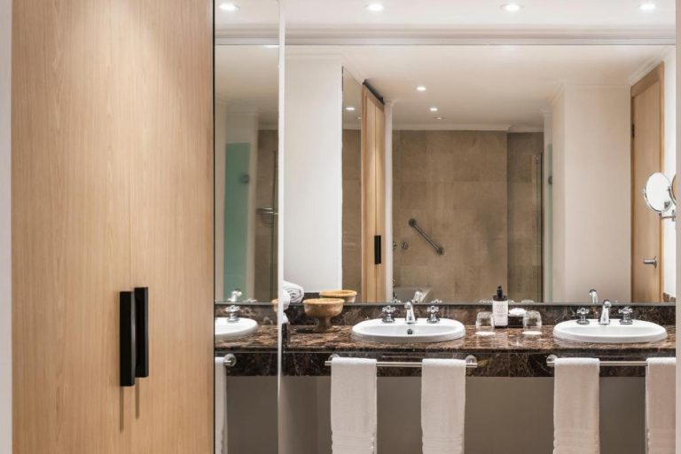 Baño de lujo con doble lavabo y encimera de mármol oscuro en el Hotel Poblado Plaza