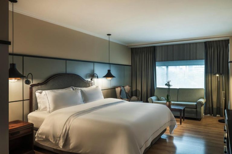 Habitación deluxe con cama king size y zona de estar del Hotel Poblado Plaza en Medellín