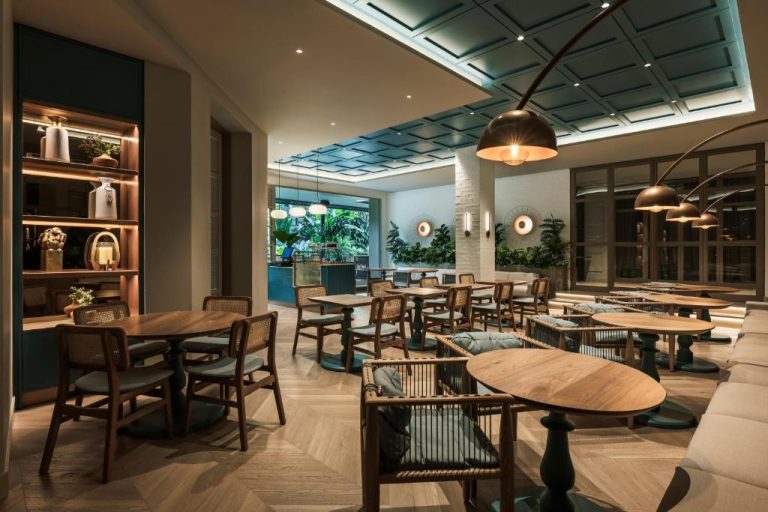Elegante restaurante interior del Hotel Poblado Plaza con mesas de madera, iluminación cálida y vegetación tropical