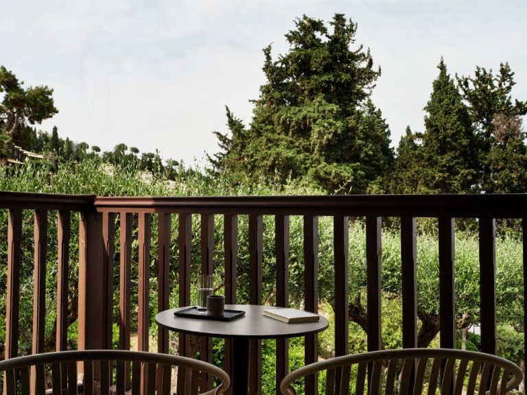 Terraza con mesa y sillas con vistas al jardín y pinos en Aeolos Beach Resort