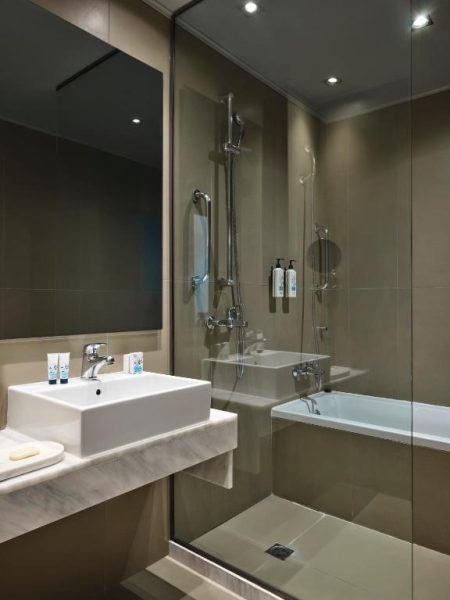 Baño moderno con ducha y bañera integrada en el Aeolos Beach Resort, acabados en mármol