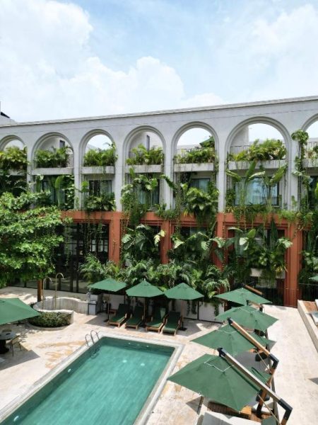 Piscina exterior rodeada de vegetación tropical y tumbonas en el Osh Hotel Cartagena, Colombia